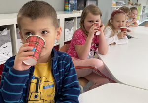 dzieci piją świeży sok z kubeczków